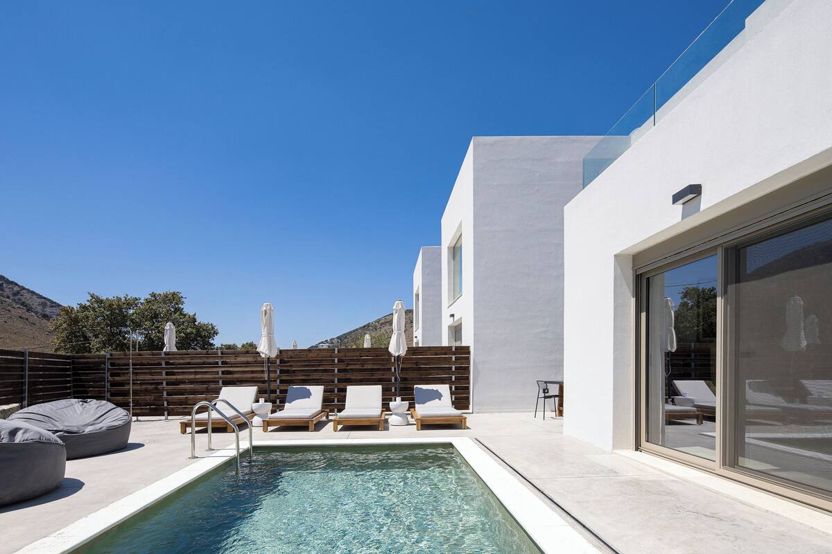 A modern outdoor pool area with lounge chairs and a wooden fence.
