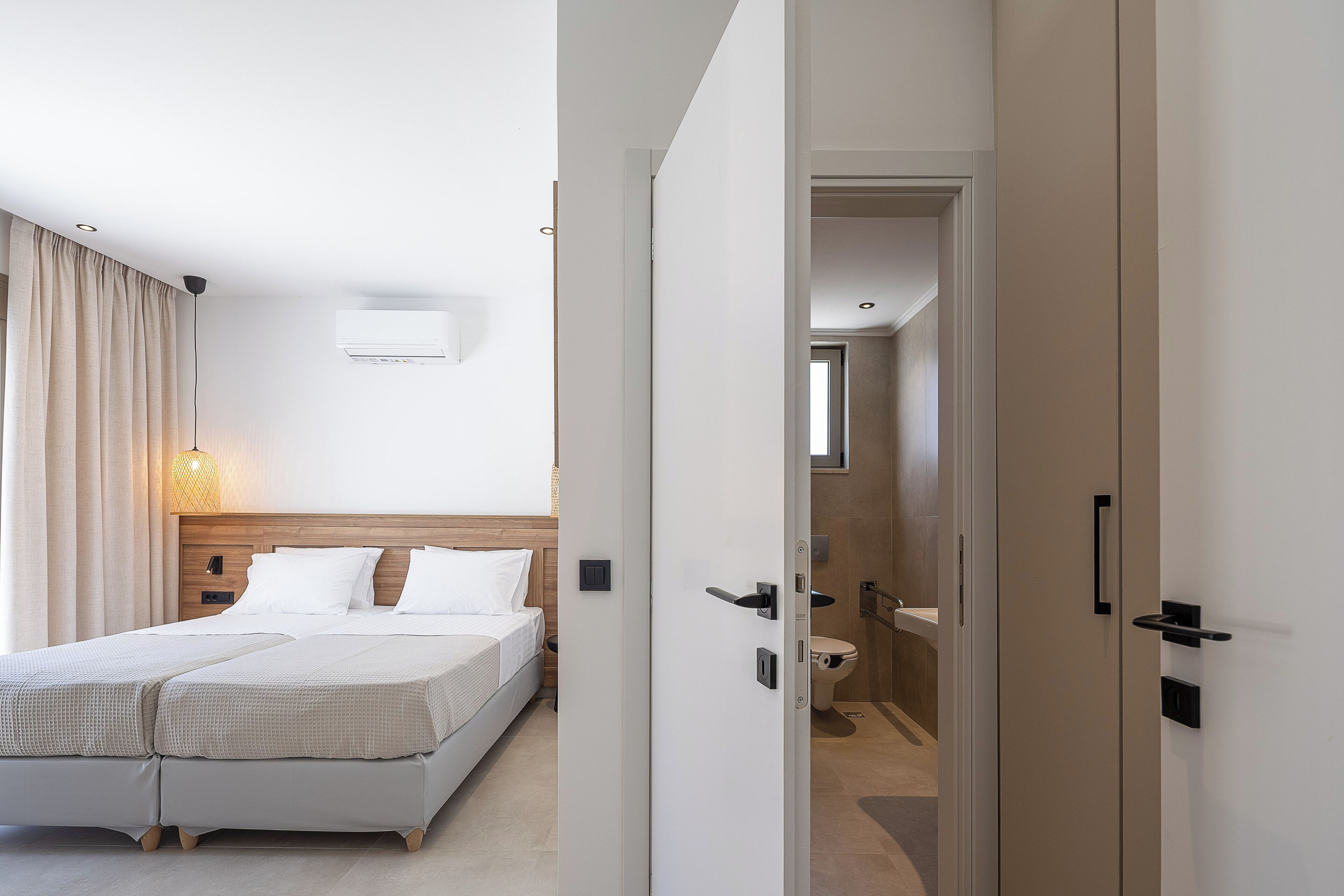 Ein modernes Hotelzimmer mit einem großen Bett, einem Nachttisch und einem durch eine offene Tür einsehbarer Badezimmer.