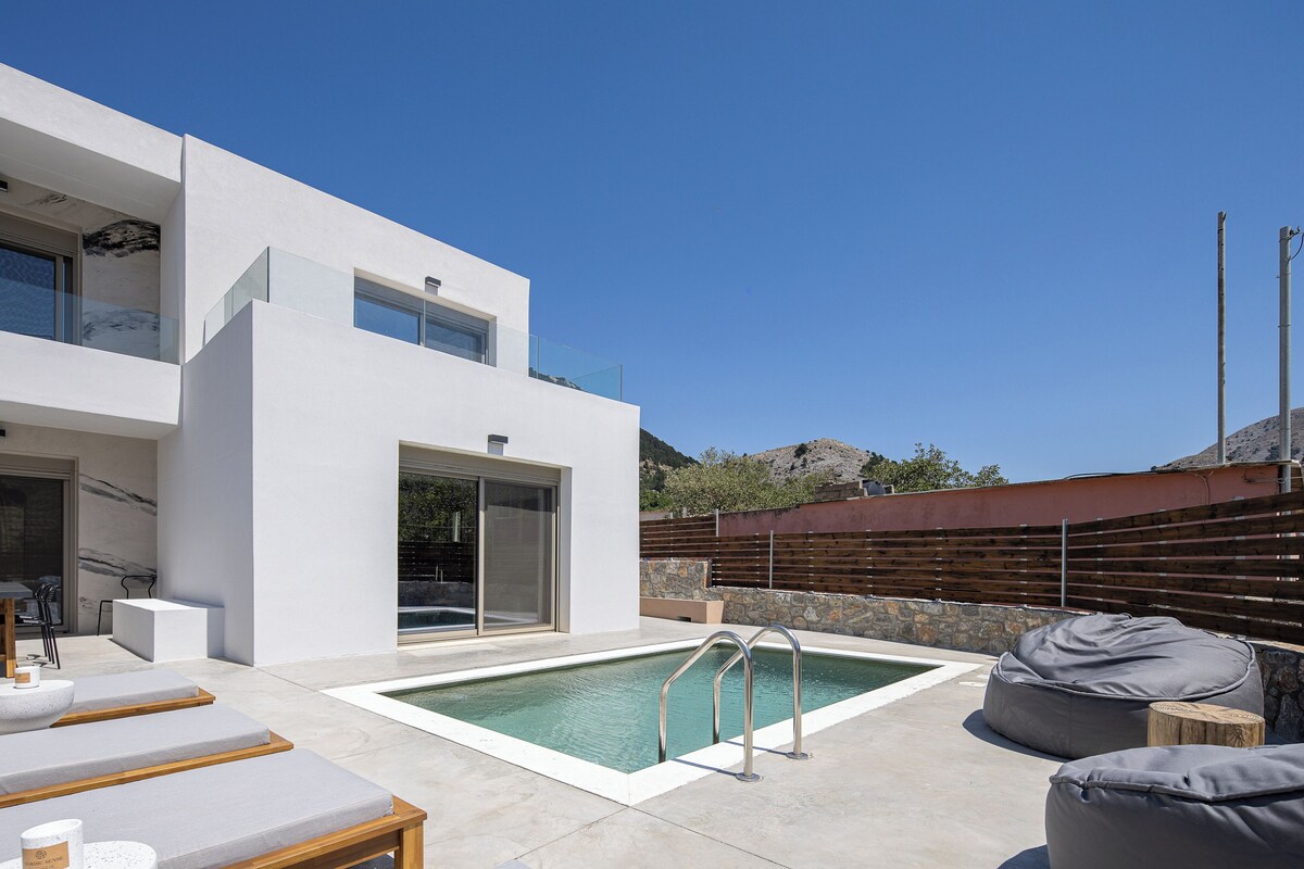 A modern outdoor pool area with a minimalist pool house, lounge chairs, and a wooden deck.