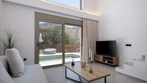 A modern living room with a large TV, a wooden coffee table, and a sofa. - Imbros Villas (Sfakia)