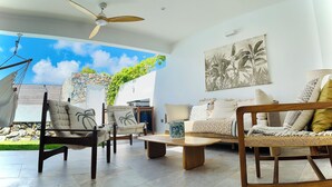 Uma sala de estar ampla com ventilador de teto, rede e vista do céu.