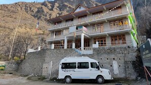 A multi-story building with balconies, a stone facade, and a van parked in front. - The Lake View Resort (Sangla)