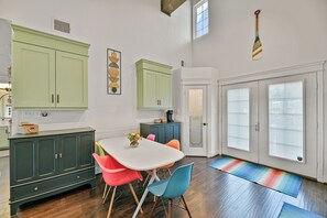 Una cucina con mobili verdi, un tavolo bianco e sedie colorate.