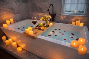 Una vasca idromassaggio con candele, un bicchiere di vino e un vassoio di snack.