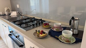 Une cuisine moderne équipée d’une cuisinière à gaz, d’appareils électroménagers en acier inoxydable et d’une machine à café.