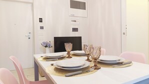 Un coin repas avec une table blanche dressée pour quatre personnes, comprenant des assiettes, des couverts et des verres.