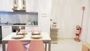 Une cuisine compacte avec des meubles blancs, une cuisinière à gaz et une table à manger pour quatre personnes.