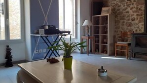 A room with a dining table, a potted plant, a lamp, a fireplace, and a stone wall. - Old restored village house with terrace (Jouques)