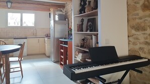 A compact kitchen with a dining area, a built-in keyboard, and a stone wall. - Old restored village house with terrace (Jouques)