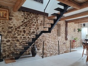 A stone wall with a black staircase, a large vase, and a dining area with chairs and a table. - Old restored village house with terrace (Jouques)