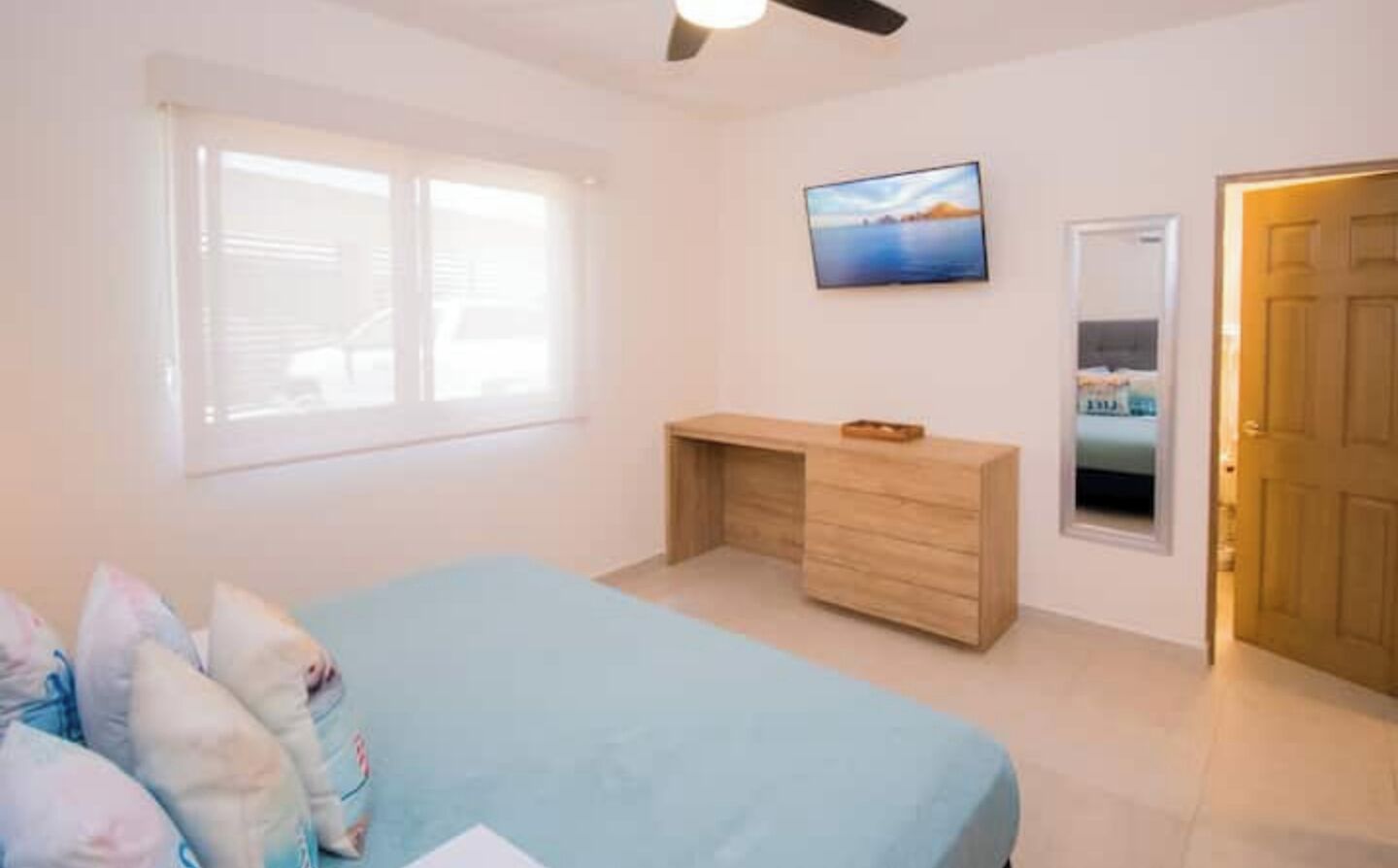 Una camera da letto con un letto, una scrivania, una televisione e una porta.