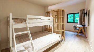Una cama litera con escalera de madera, un escritorio con silla y una ventana con cortinas.