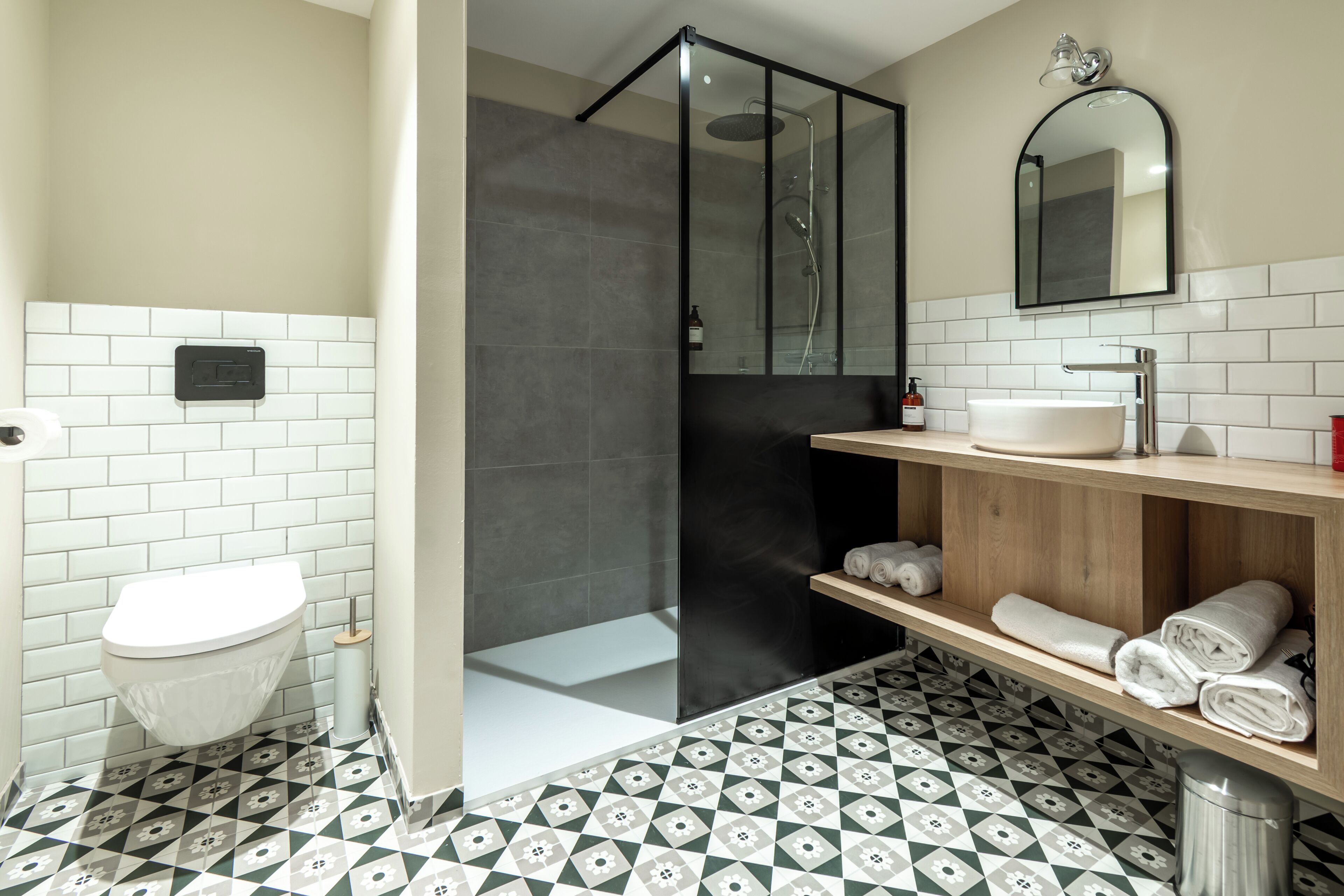 Ein modernes Badezimmer mit Toilette, Dusche, Waschbecken und Spiegel.