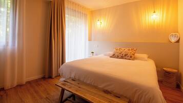 A bedroom with a bed, wooden bench, curtains, wall-mounted light, and a heart-shaped decoration.