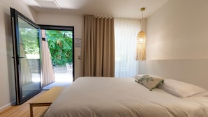 A bedroom with a large bed, a sliding glass door to a balcony, and a hanging light fixture. - Nina's Hideaway Hotel - Madame's Dream (Saint-Girons)