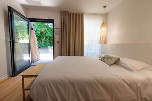 Un dormitorio con una cama grande, un ventanal corredero a un balcón y una lámpara colgante.