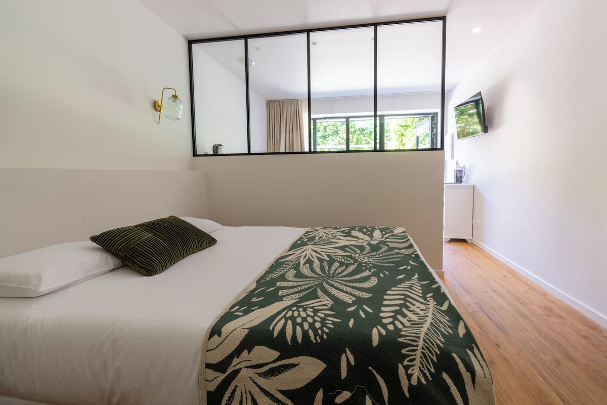 Une chambre à coucher avec un lit, une fenêtre, un téléviseur et un miroir.