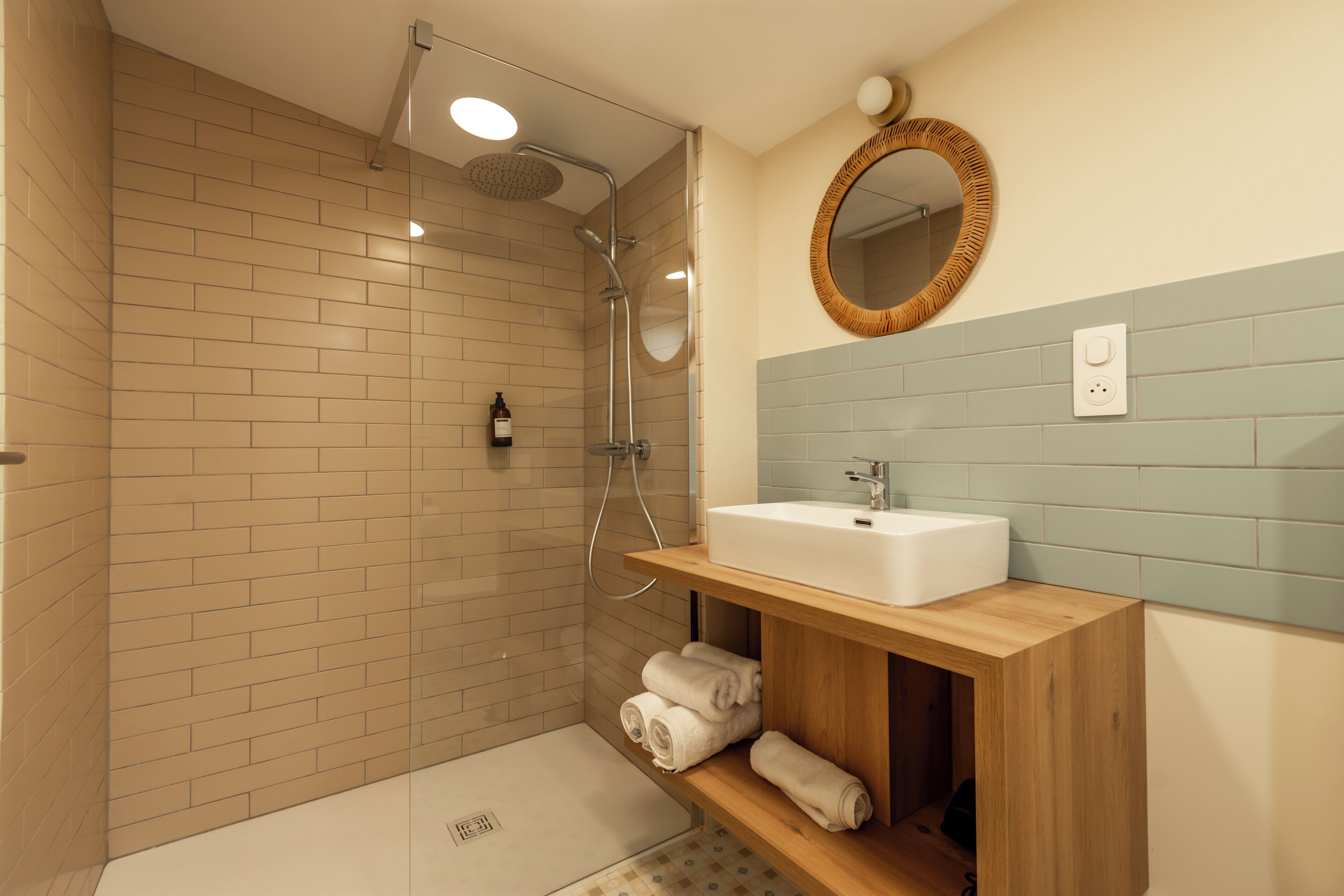 Un baño moderno con ducha, lavamanos, espejo y toallero.