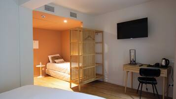 A room with a bed, a desk with a chair, a television, and a wooden partition.