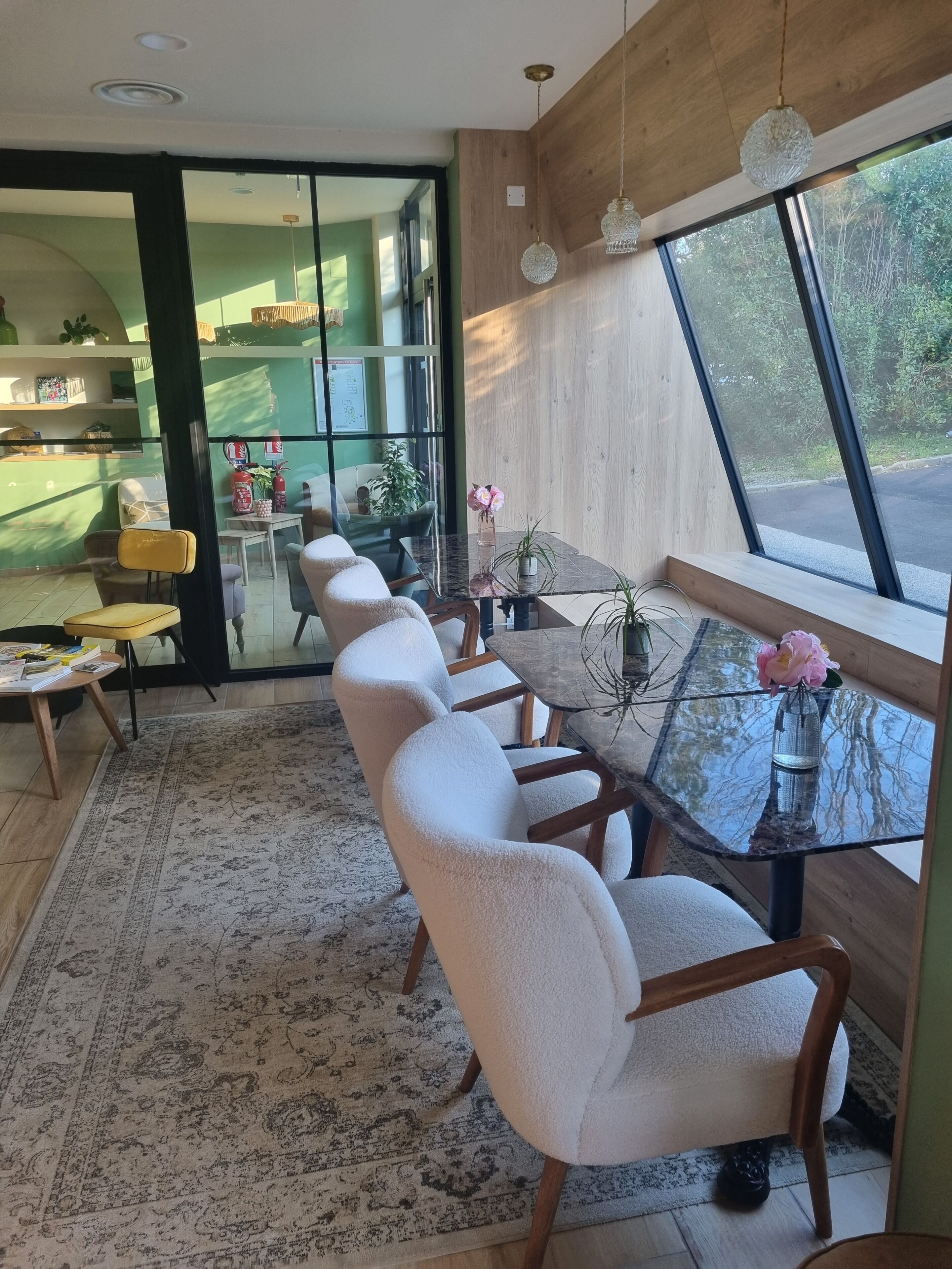 Un interior moderno con una mesa de comedor de cristal, sillas cómodas, un tapete estampado y vistas a través de grandes ventanales.