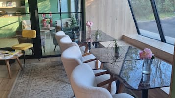 Un interior moderno con una mesa de comedor de cristal, sillas cómodas, un tapete estampado y vistas a través de grandes ventanales.