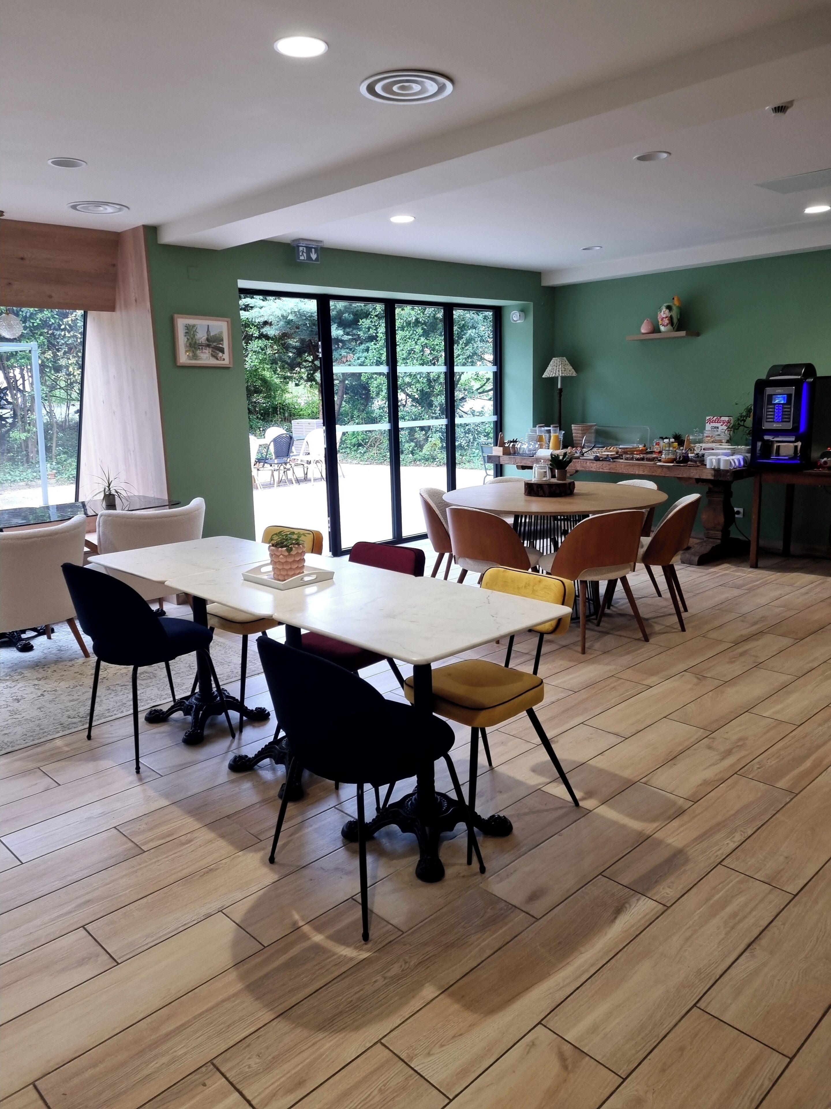A dining area with a table and chairs, a view through large windows, and a ceiling with recessed lighting.