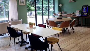 A dining area with a table and chairs, a view through large windows, and a ceiling with recessed lighting.