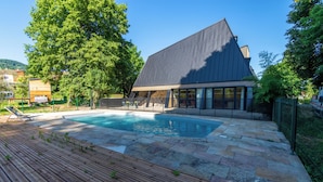 A modern building with a swimming pool, surrounded by a wooden deck and stone tiles. - Nina's Hideaway Hotel - Madame's Dream (Saint-Girons)
