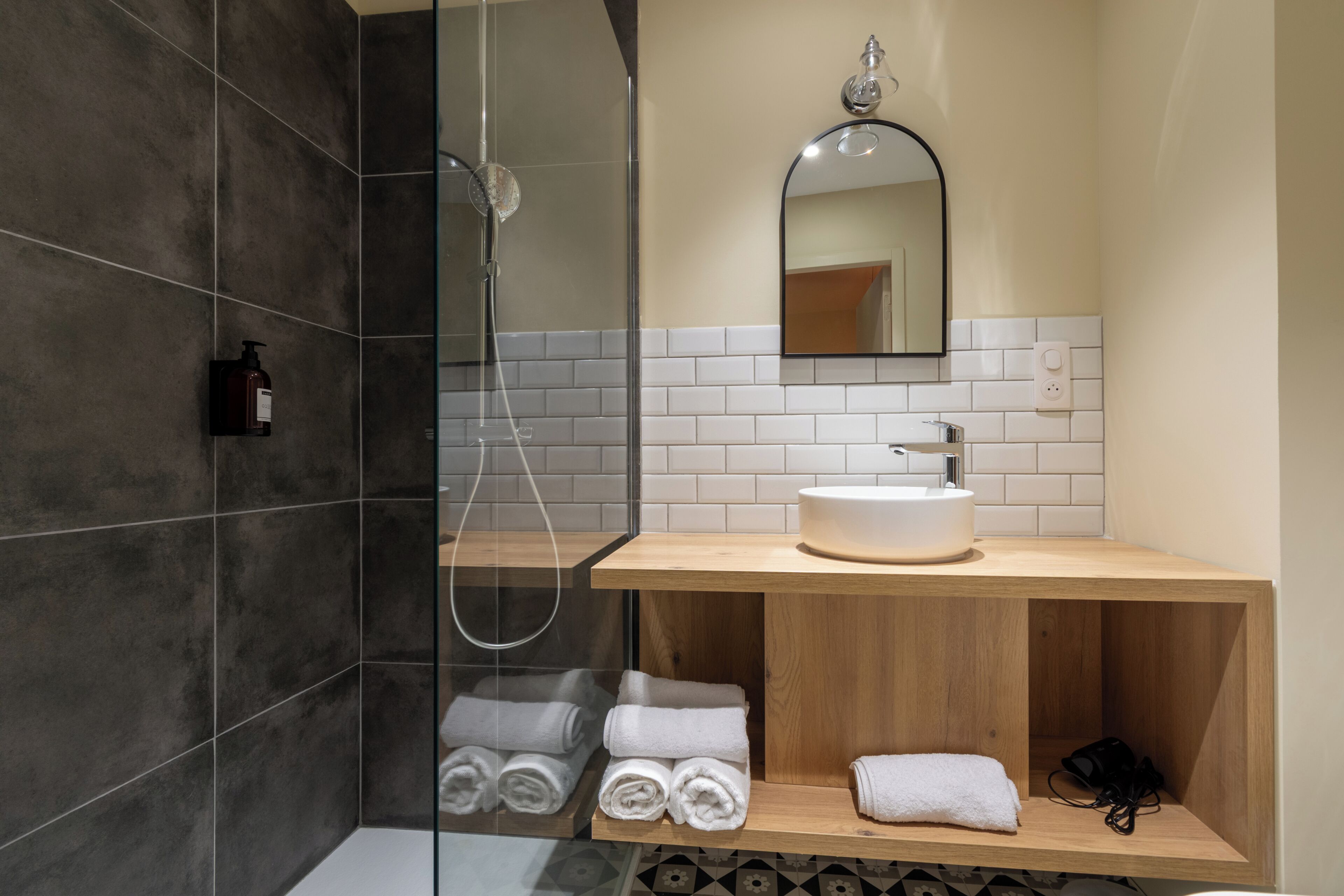 A modern bathroom with a glass-enclosed shower, a wooden vanity with a sink, and neatly folded towels.