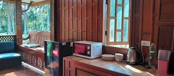 Traditional Thai wooden house on stilts set in a coconut orchard near the beach