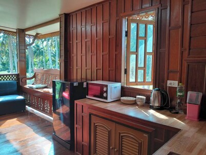 Traditional Thai wooden house on stilts set in a coconut orchard near the beach