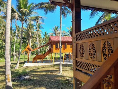 Traditional Thai wooden house on stilts set in a coconut orchard near the beach 