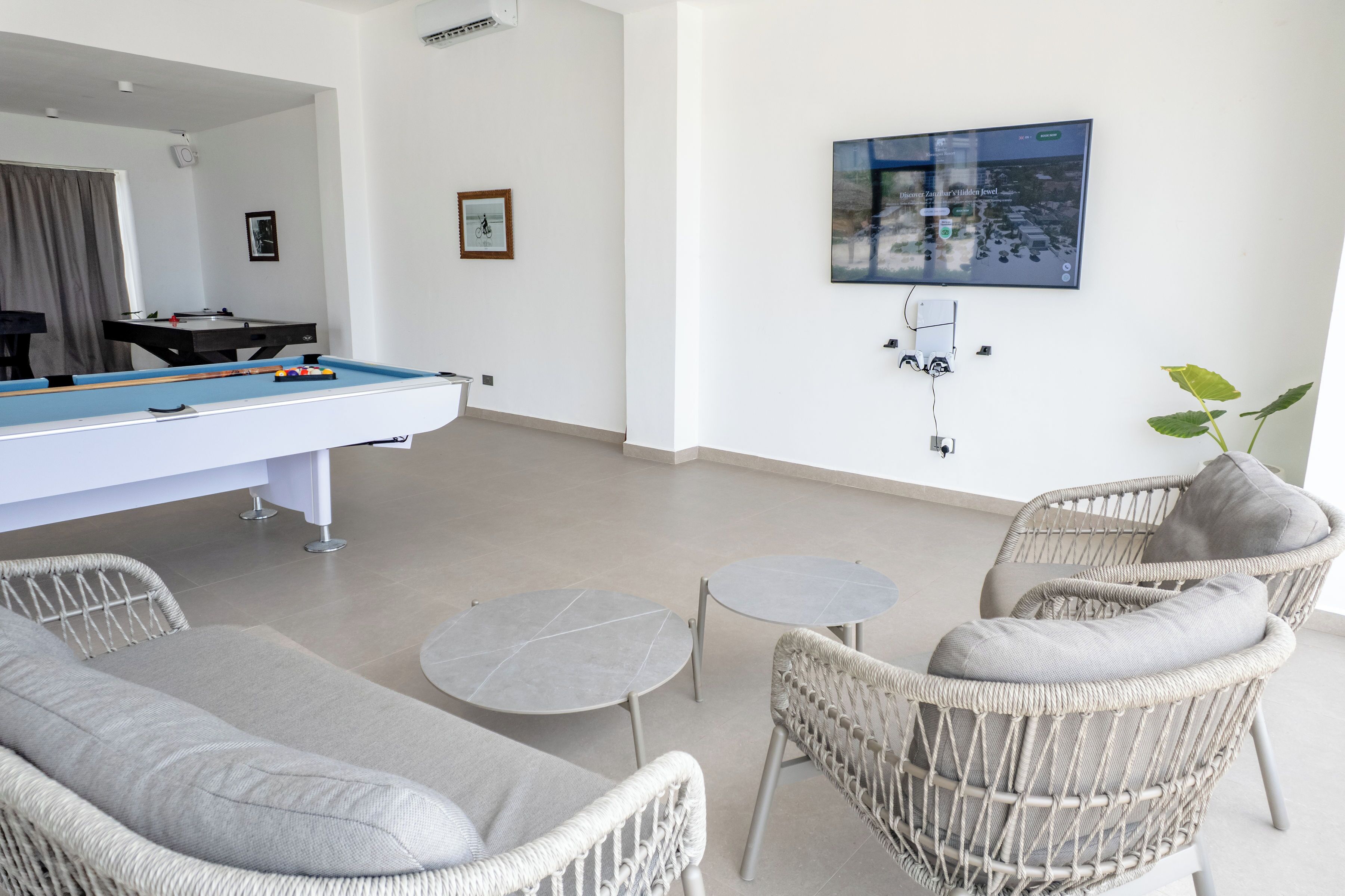 Una mesa de billar, sillones de descanso, un televisor y una planta en una habitación moderna.