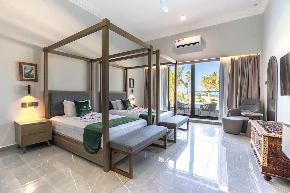 Een moderne hotelkamer met een hemelbed, een balkon met zitje en een flatscreen televisie.