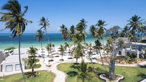 Un resort con vista a la playa, palmeras y un camino que lleva a la arena.