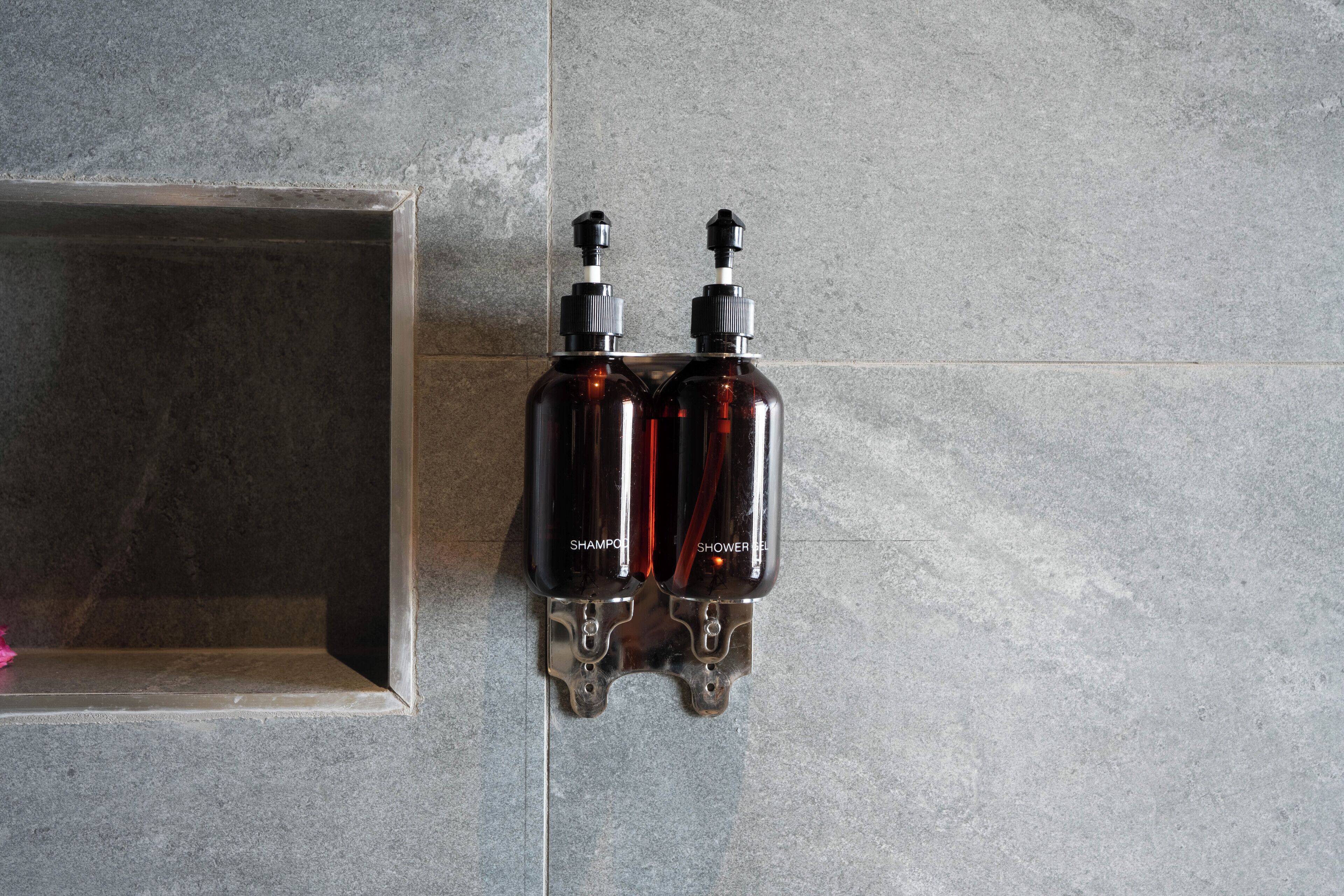 Two dark brown bottles with labels, mounted on a tiled wall.