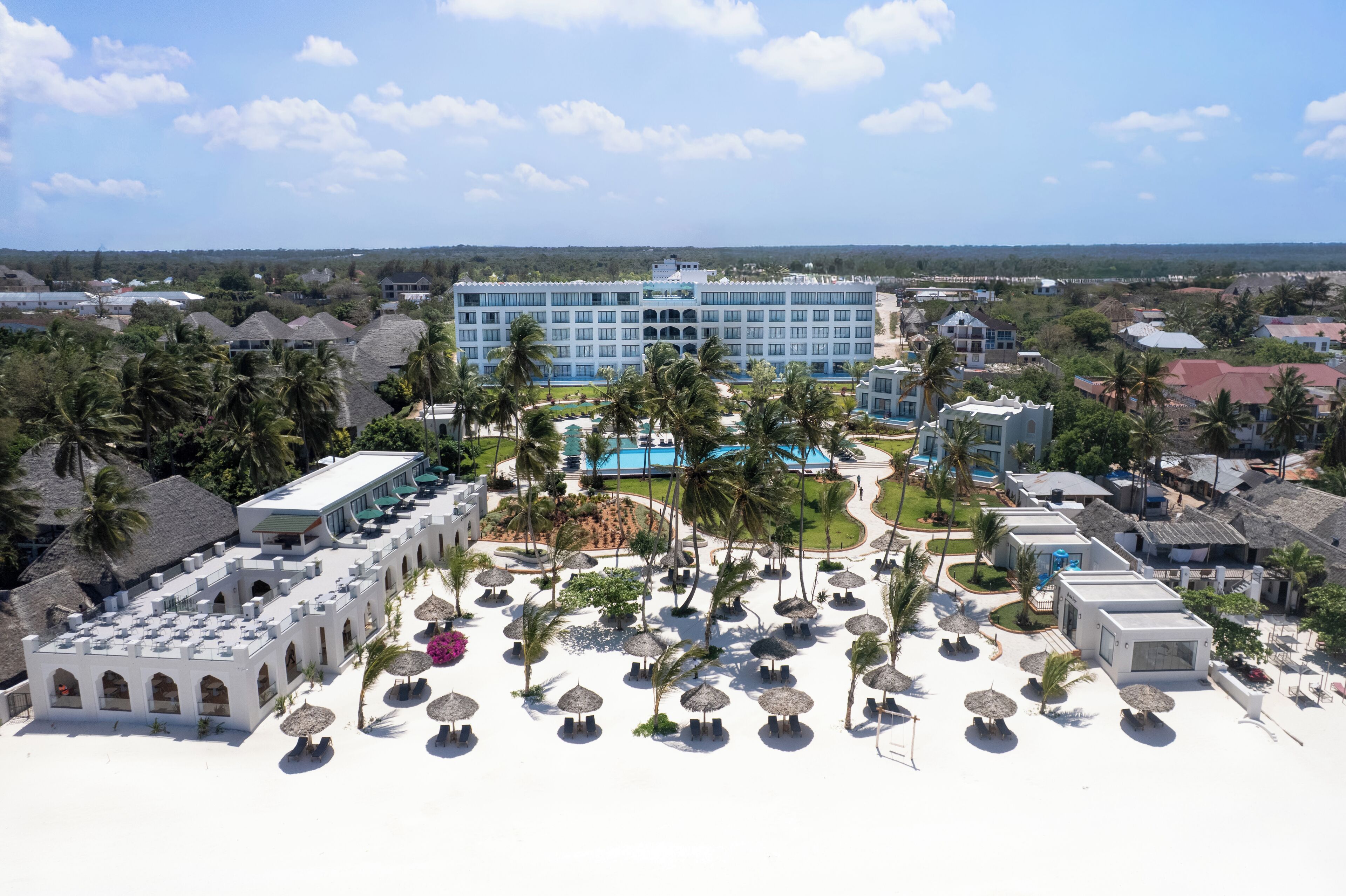 Un resort con un edificio grande, palmeras y un área de piscina.