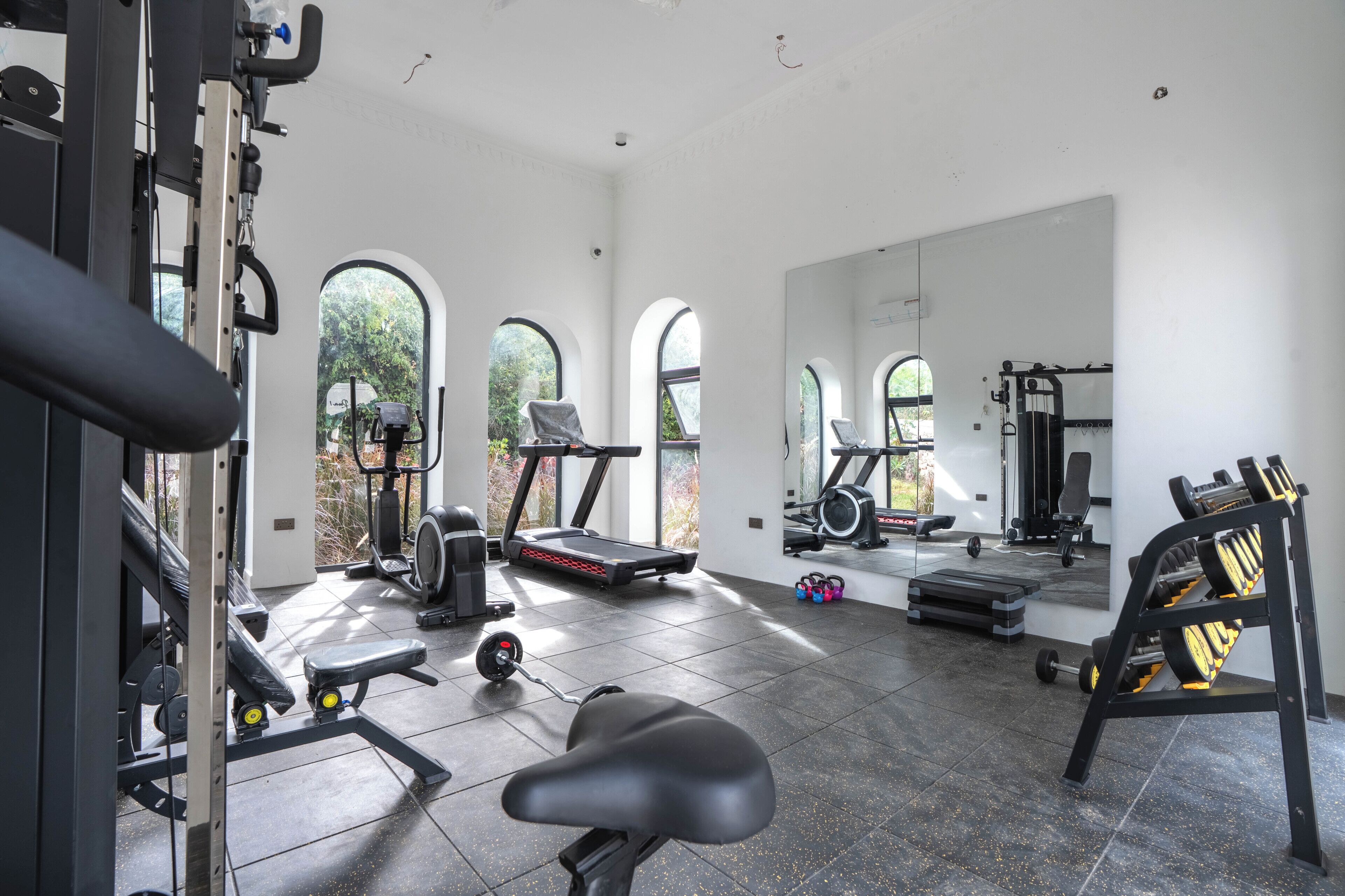 A spacious gym with various exercise equipment, large windows, and a clean, modern design.