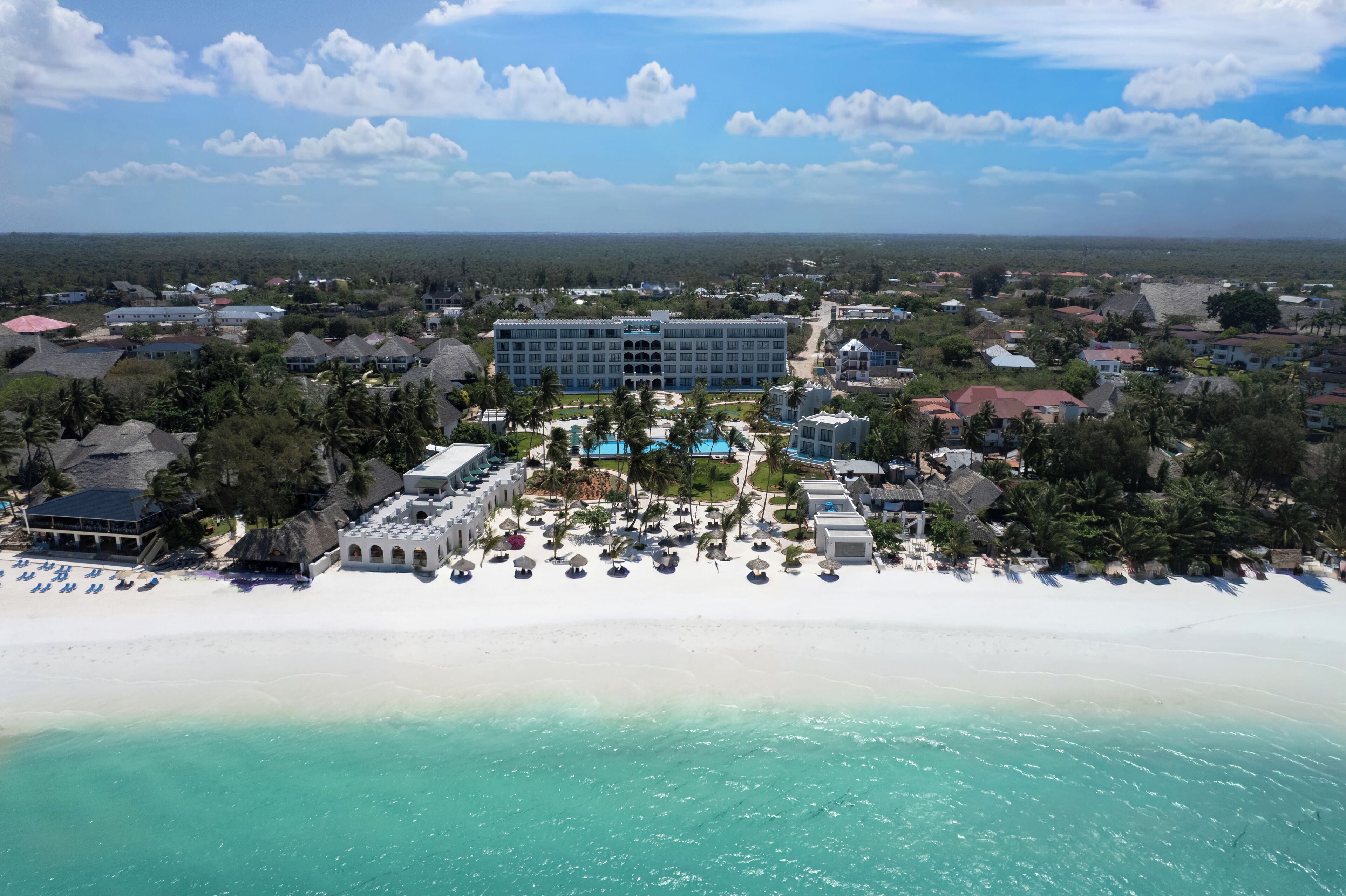 Ein Resort mit einem großen Gebäude, einem Strand und einem Poolbereich.