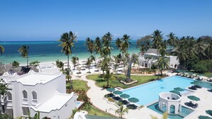 Un resort con piscina, playa y palmeras.