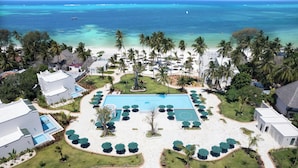 Un resort con piscina central, rodeado de palmeras y vistas a la playa.