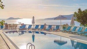 Un área junto a la piscina con sillones de descanso, una piscina y vista al mar.