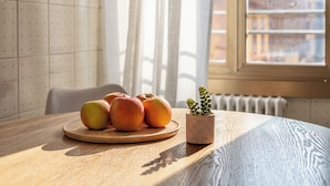 A wooden table with a plate of apples and a small potted plant.