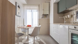 A modern kitchen with white cabinetry, a dining table with chairs, and an oven.