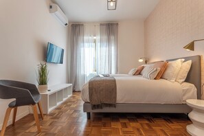 A modern bedroom with a bed, bedside table, TV, and a potted plant. - Luminoso appartamento al Pigneto (Rome)