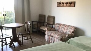 A hotel room with a bed, two chairs, a table, and a view of the outdoors. - vereda bike park hotel (São João del Rei)