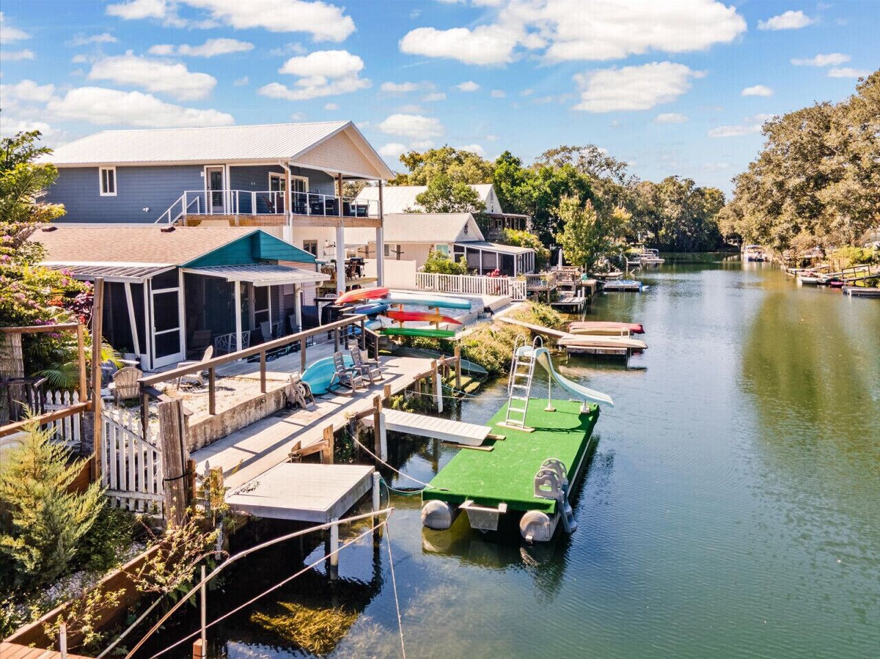 A lakeside property with a dock, a covered seating area, and a house with a balcony.