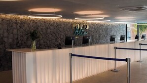 A reception area with a stone wall, a reception desk, and a neon sign that reads "PORTO Altos". - Flat Porto Alto Resort, Porto de Galinhas   (N. São do Ó)