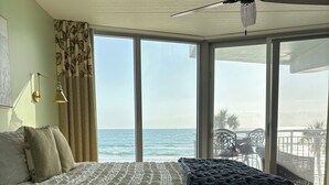 Un dormitorio con una cama grande, ventilador de techo y vista al océano.
