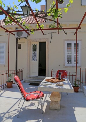 A terrace with a table, chairs, a wine bottle, and potted plants. - Vicina Summer Apartments - One Bedroom Apartment With Sea View (Dubrovnik)